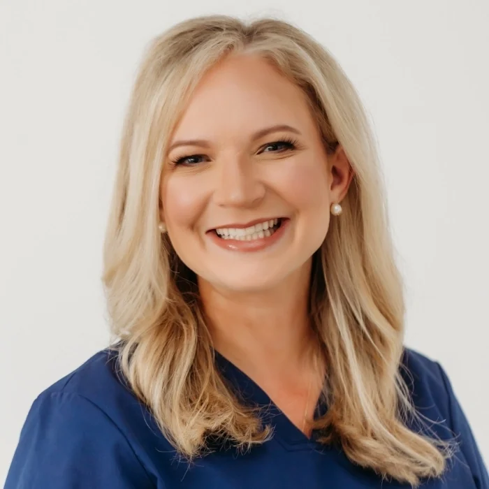Dr. Ashley Hill Lindsey, lead dentist at Athens Dental Associates, smiling in navy scrubs.