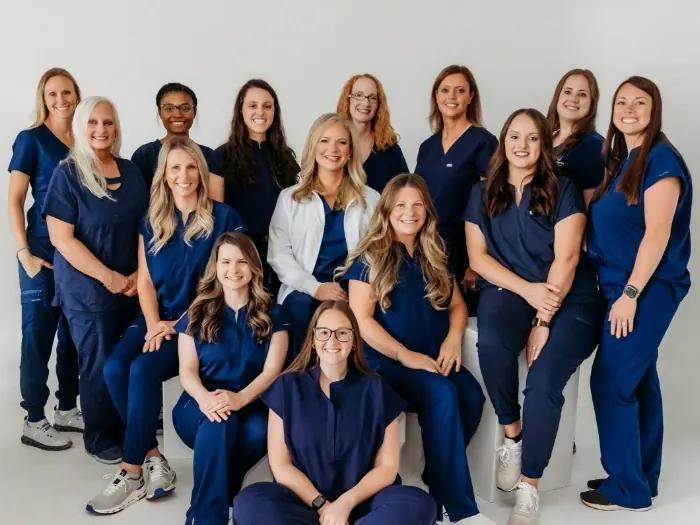 Members of the Athens Dental Associates team in navy scrubs, standing and seated together.