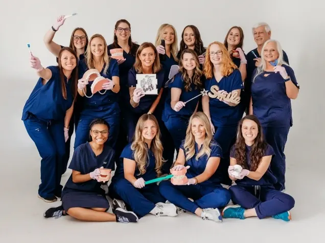 The Athens Dental Associates team together in navy scrubs for a group photograph.