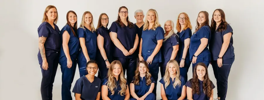 The Athens Dental Associates team standing in a row in navy scrubs.